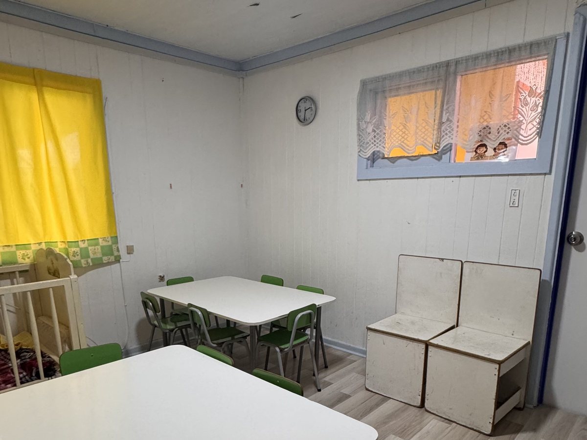 Sala luminosa con mesa de trabajo y repisas blancas