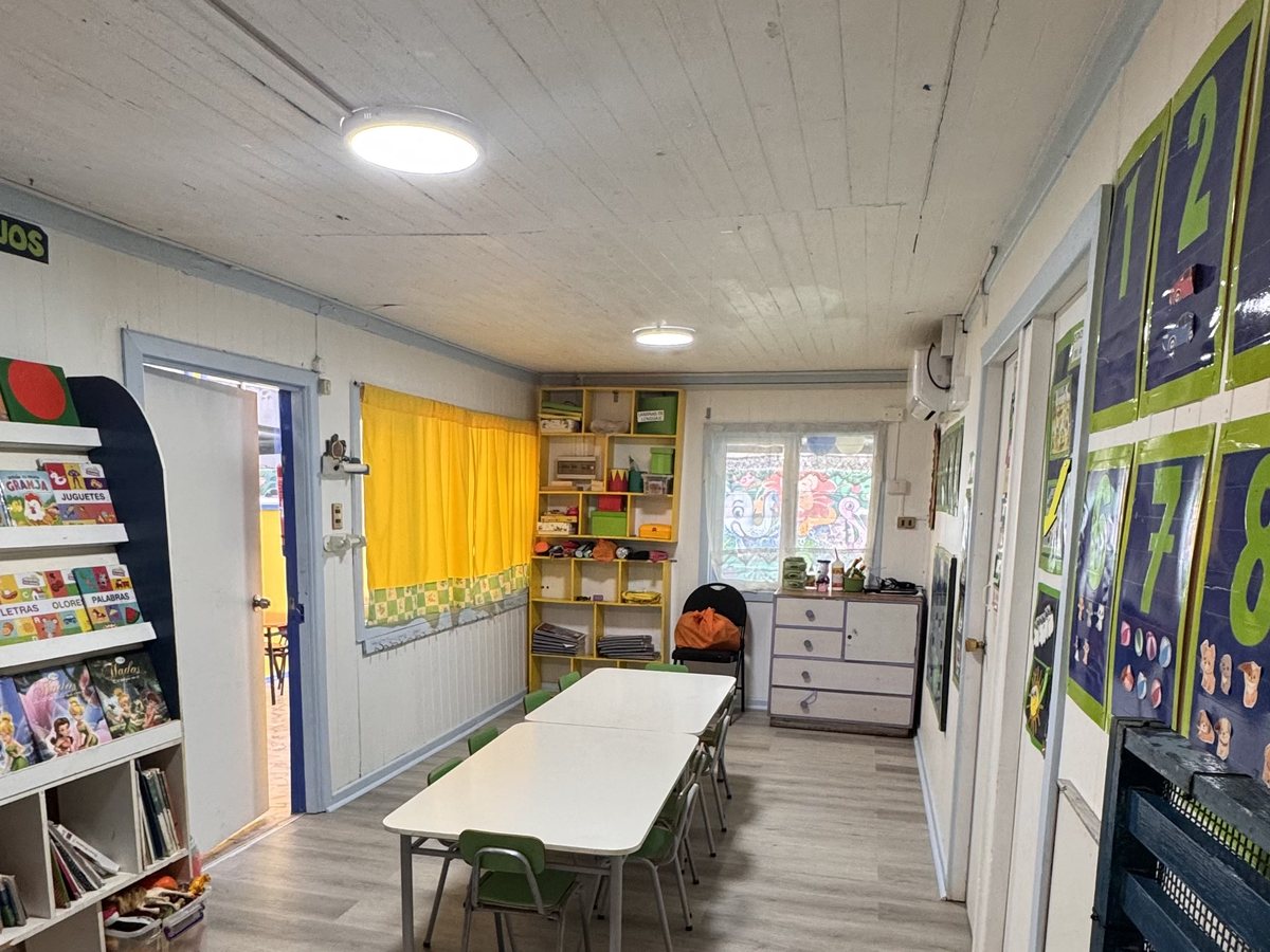 Sala de kínder, con mesas largas de trabajo y piso de madera